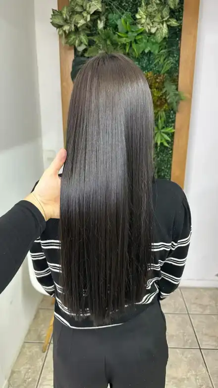 Cabelo escuro e liso de costas diante do muro