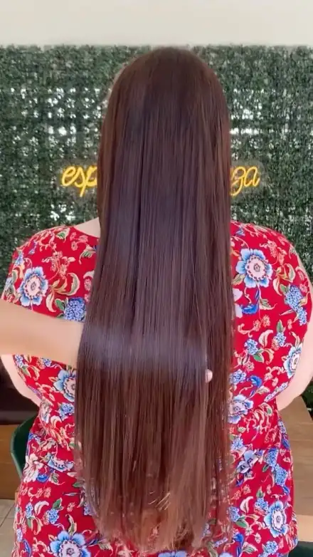 Cabelo liso de costas diante do muro de folhagem